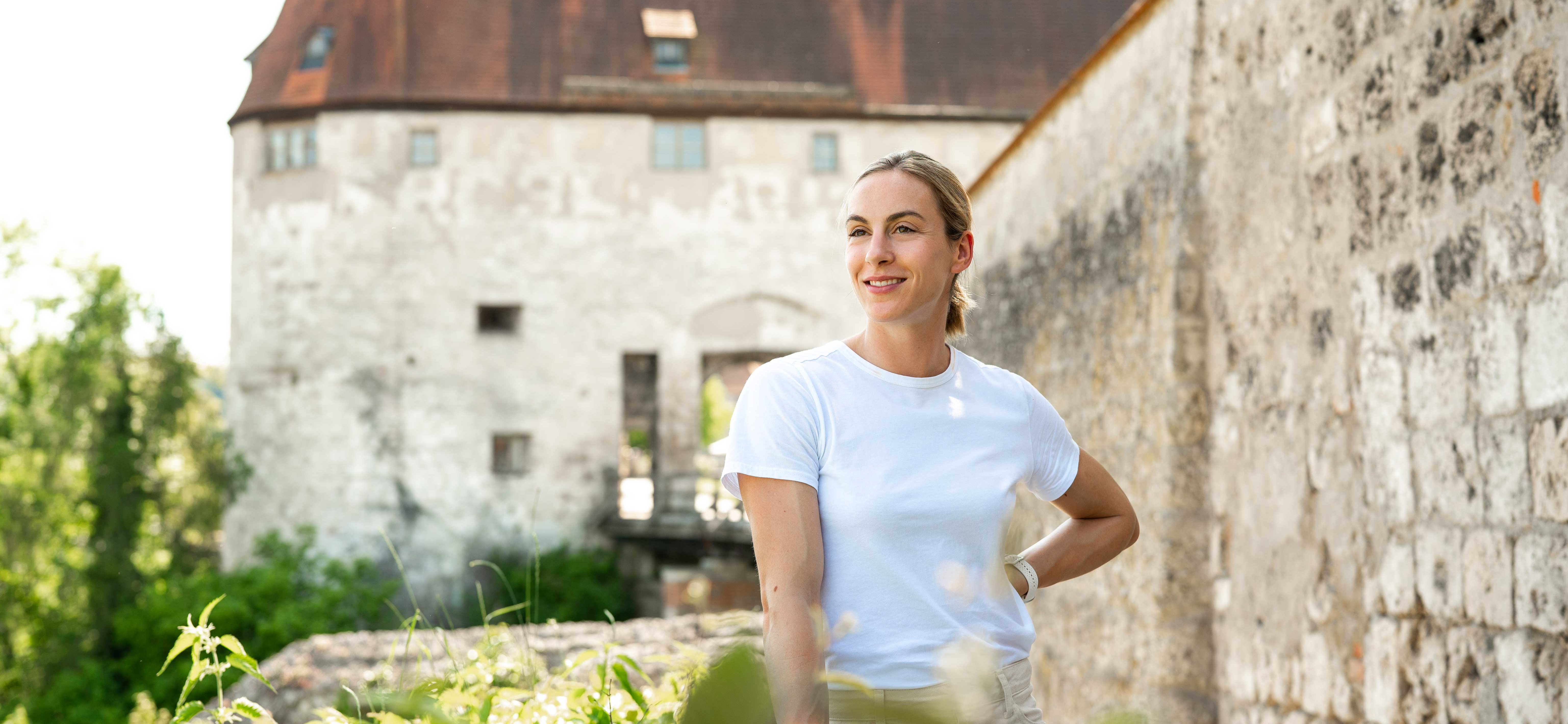 Eine Frau steht neben der Burg zu Burghausen